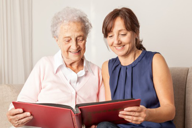 Woman looking through photo album with senior woman