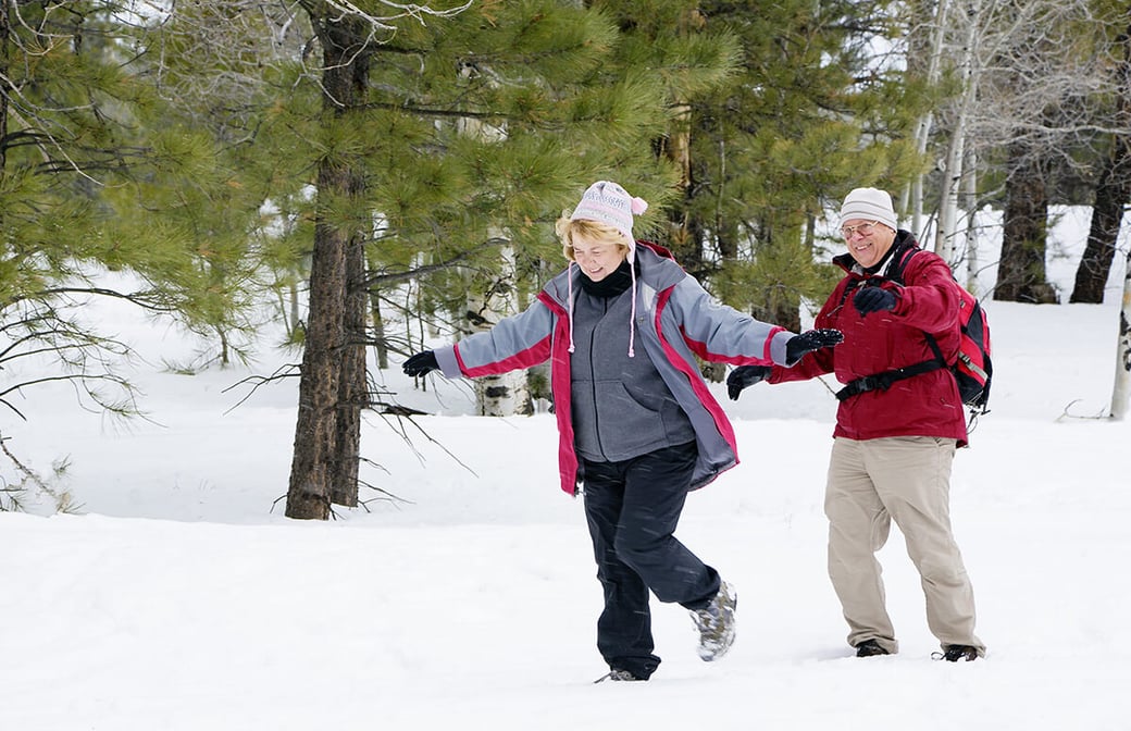 Senior couple hiking through snow