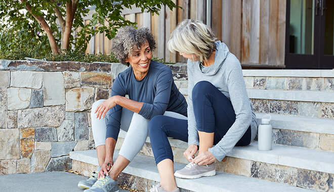Two women tying their shoes on their front steps
