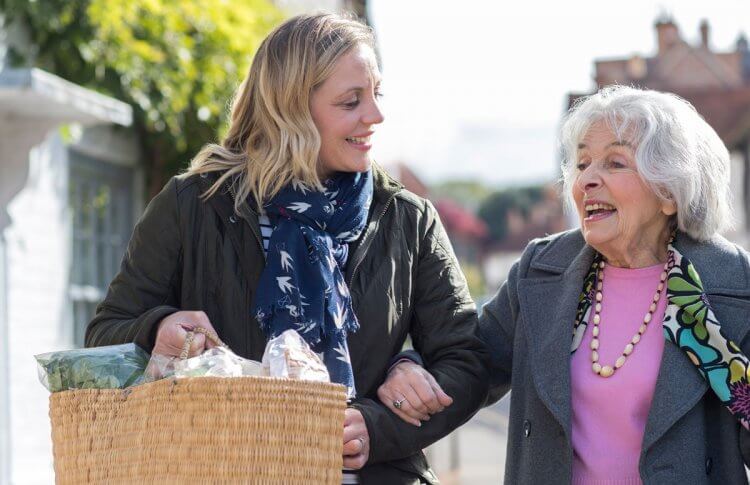Woman assisting senior woman with groceries