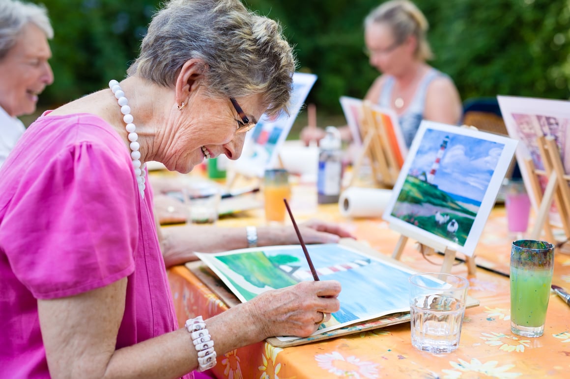 Senior women painting an image of a lighthouse