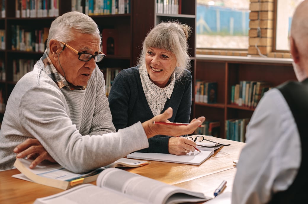 Seniors discussing textbook topics in a library