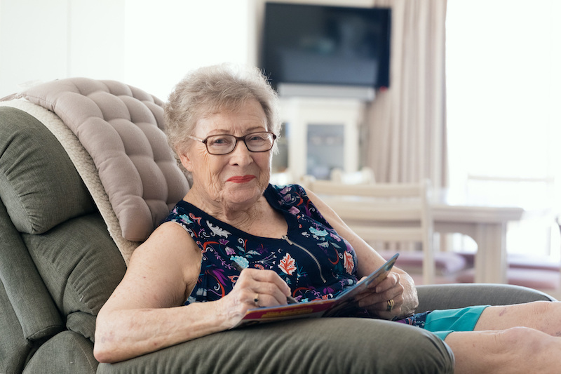 Senior woman sitting in recliner and writing in notebook