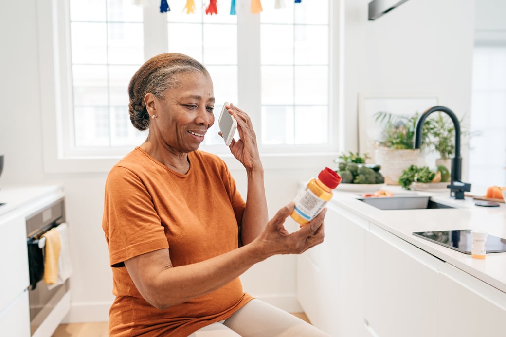 Senior woman speaking on the phone while inspecting prescription medication bottle
