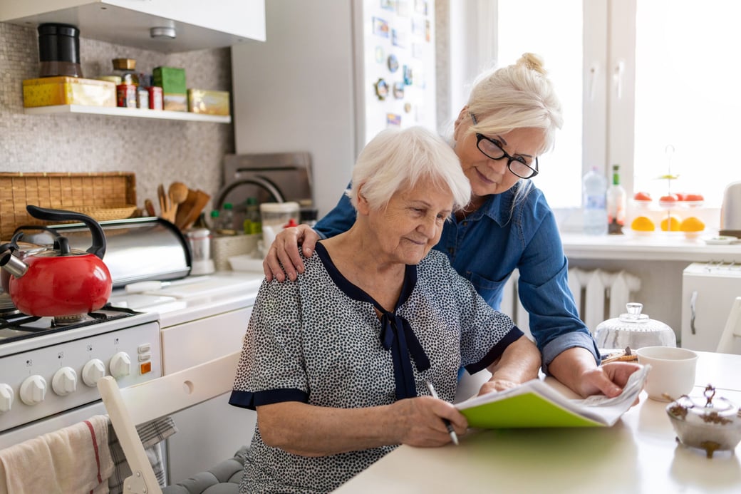 Woman assisting senior woman with creative writing