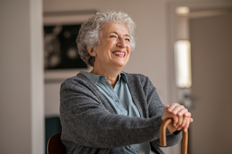 Senior woman leaning on cane and smiling