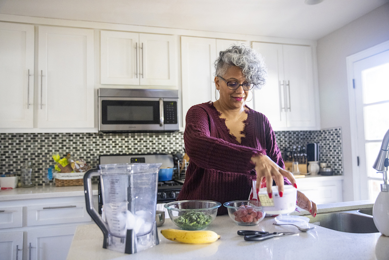 Senior woman making a smoothie in a kitchen