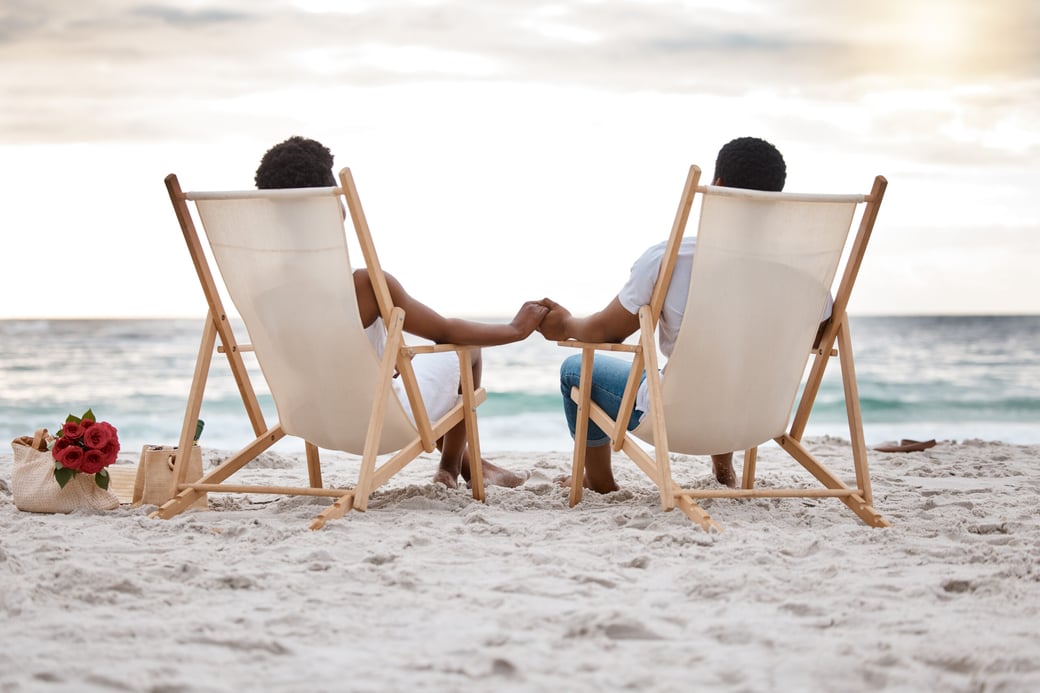 Adult couple holding hands while sitting on the beach