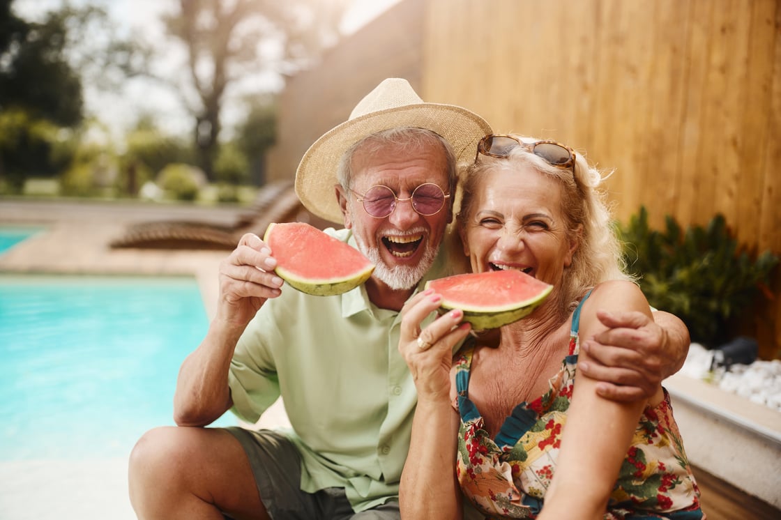 Senior couple eating watermelon by a pool