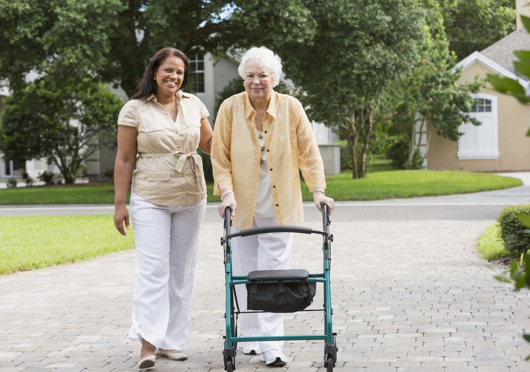 Young woman walking with senior woman down a neighborhood path