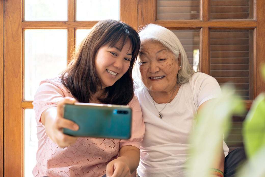 Granddaughter and grandmother taking photo on smartphone