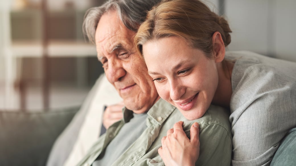 Woman hugging senior man over a couch