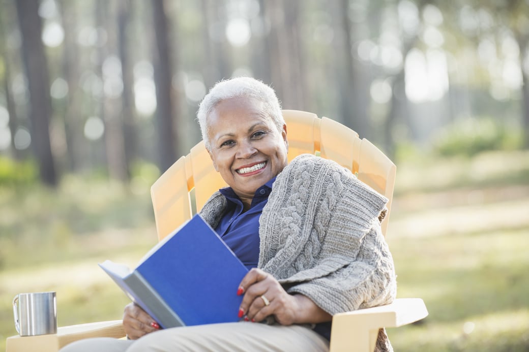 Senior Woman Reading a Book Outdoors in Nature