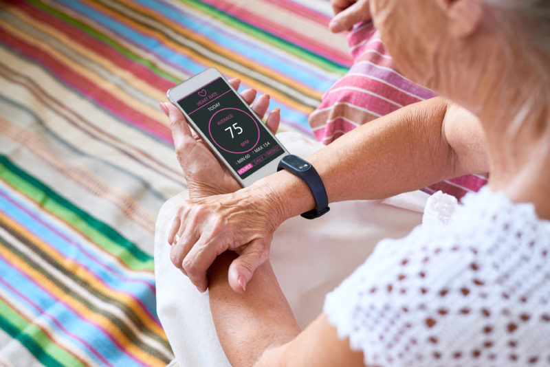 Senior woman checking her heart rate on a smartphone that is connected to a smart watch