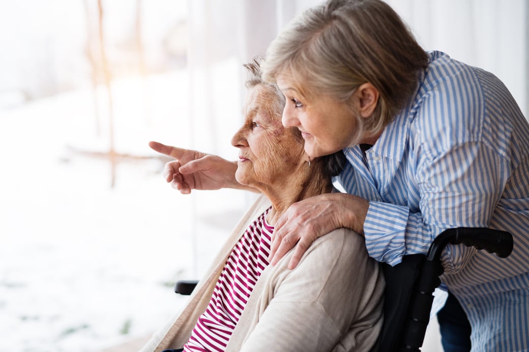 Adult Daughter Looking Out Window with Senior Mother