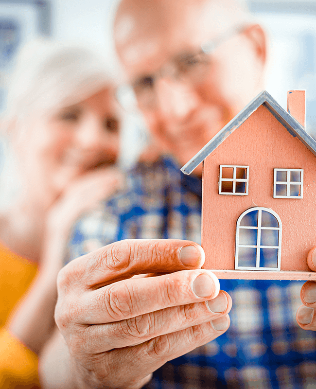 senior couple holding a little house toy